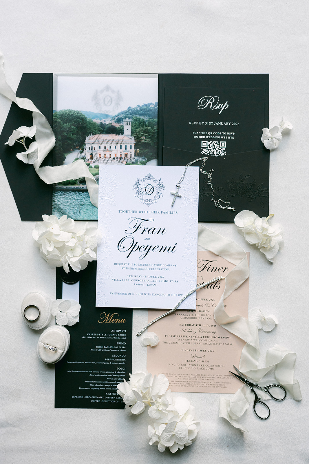 Fran and Ope's wedding stationery arranged with white flowers and green accents.