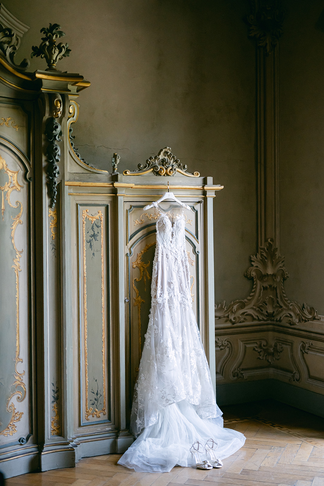 Fran's lace wedding gown hanging against an ornate cabinet inside Villa Erba, Lake Como.