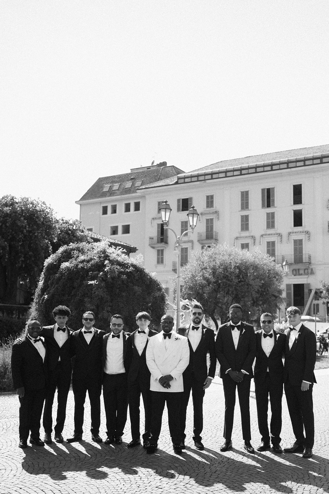Black and white group portrait of Ope and his groomsmen outside their Lake Como hotel.