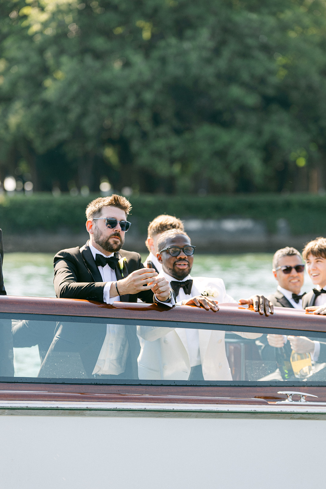 Ope raising a glass aboard a wooden boat on Lake Como with his groomsmen.