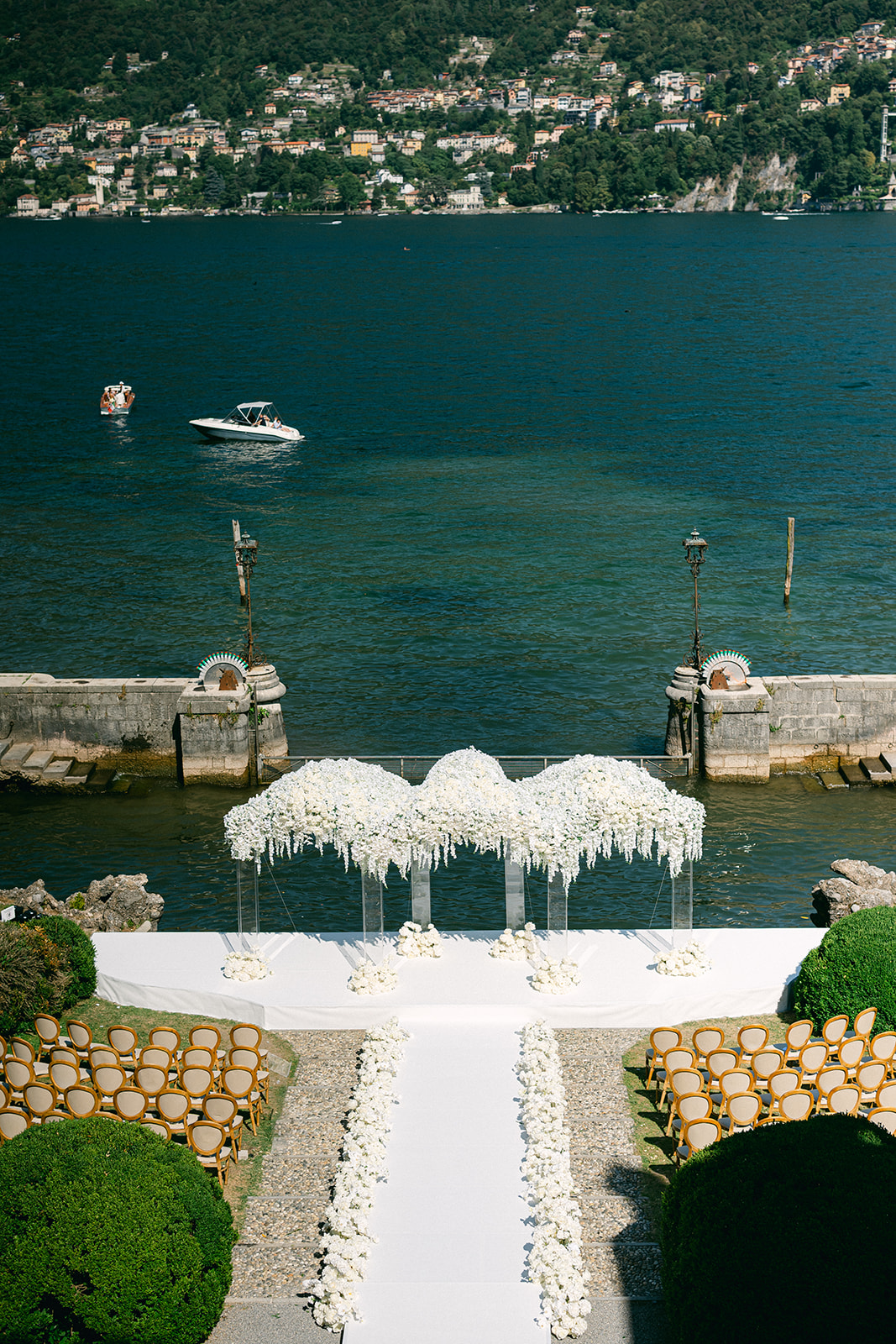 White floral wedding arch and petal-lined aisle overlooking Lake Como at Villa Erba.