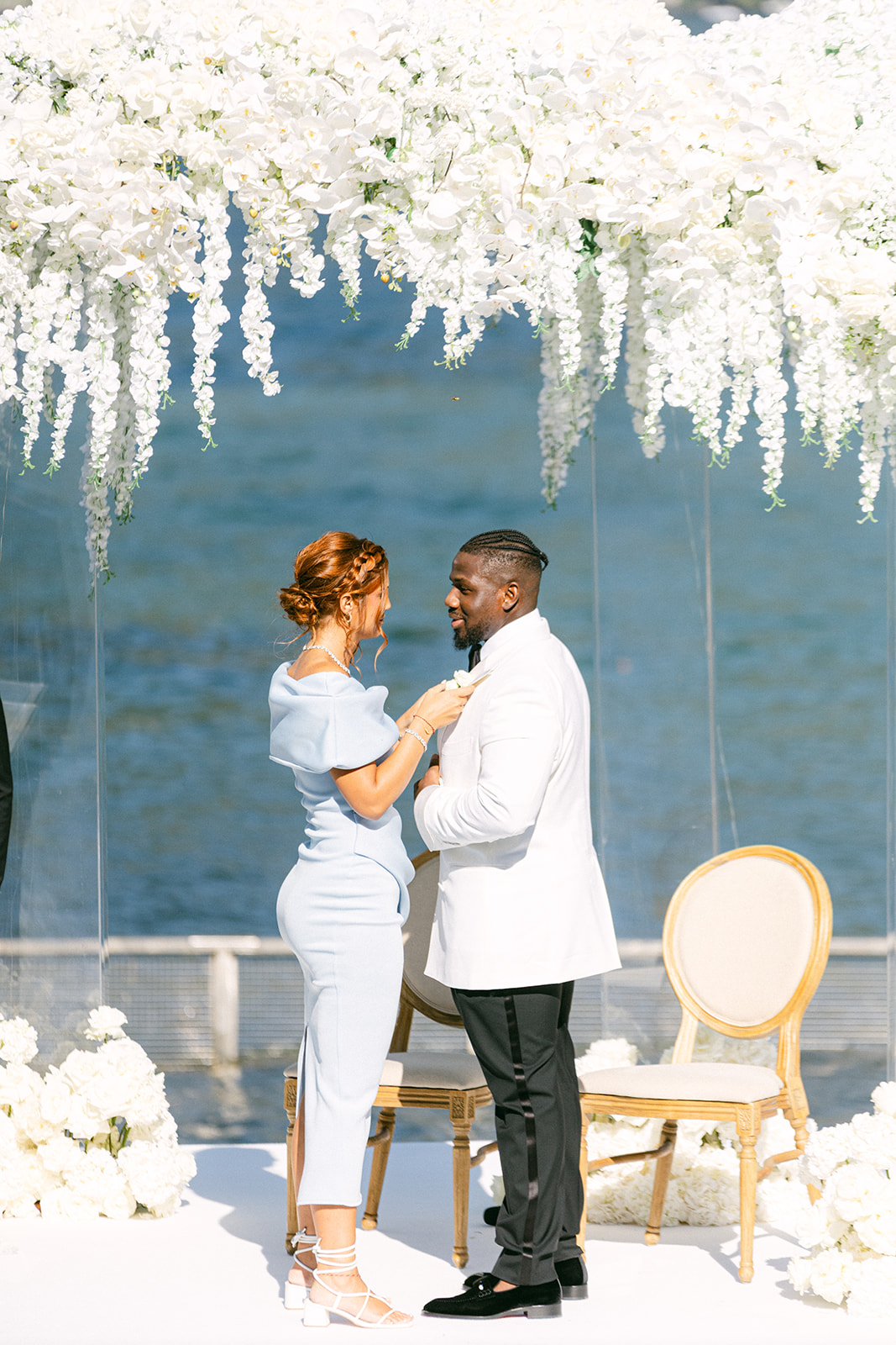 Ope speaking with the officiant beneath the white floral arch at Villa Erba.