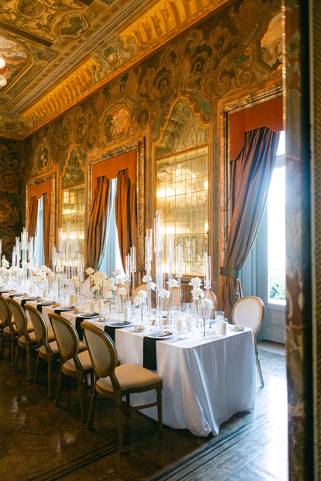 Wedding reception tables set beneath painted ceilings in the ornate dining room of Villa Erba.