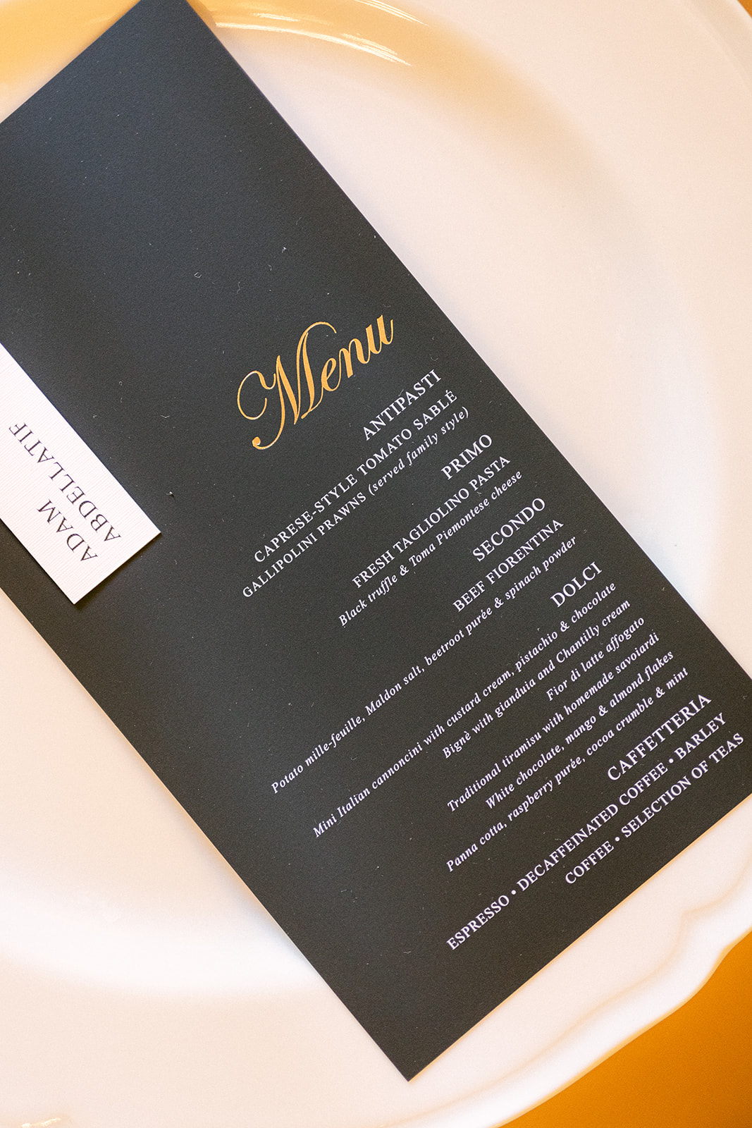 Black and gold wedding dinner menu on a white table setting at Villa Erba.