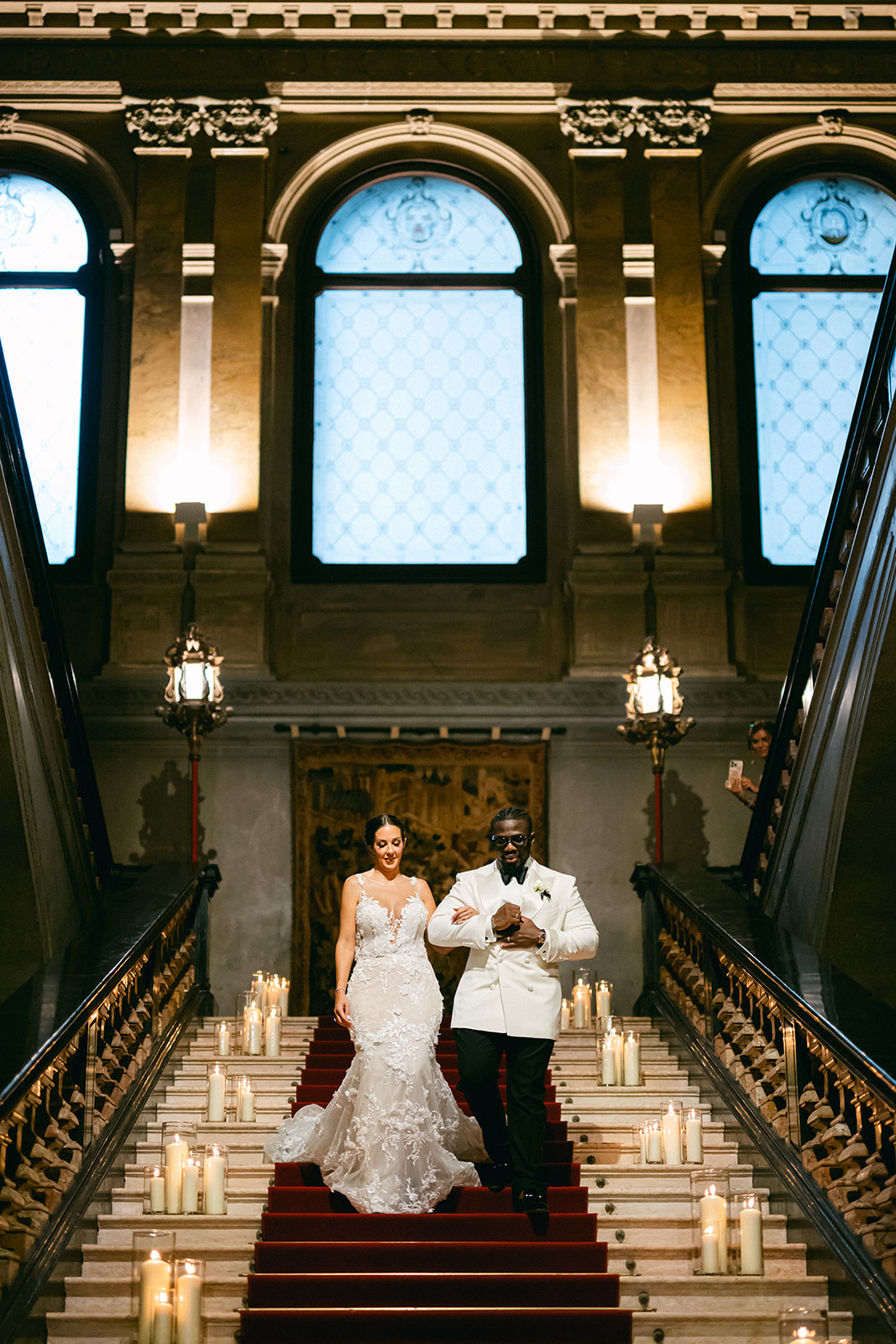 Fran and Ope descending the illuminated grand staircase inside Villa Erba.