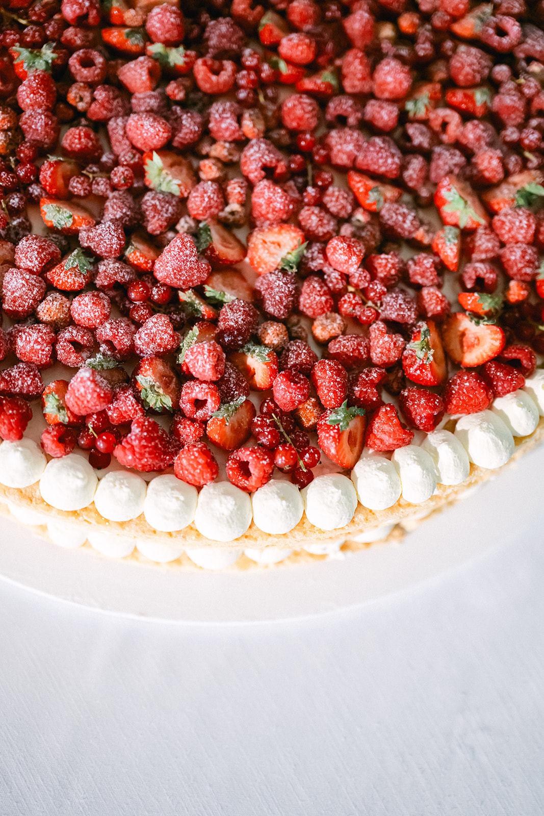 Close-up of a wedding cake topped with strawberries, raspberries and cream.