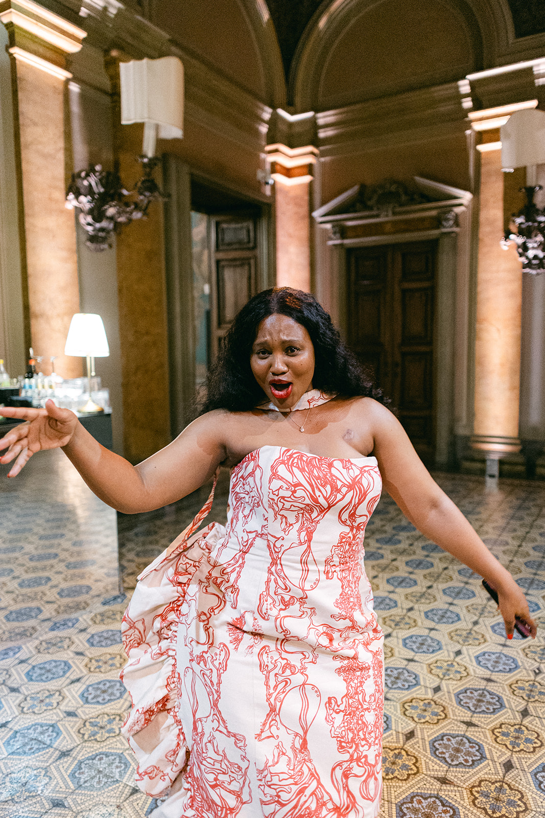 Wedding guest in a pink patterned dress holding a glass inside Villa Erba.