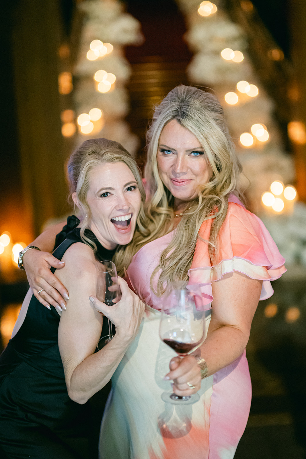 Two wedding guests laughing together with drinks during the evening reception at Villa Erba.